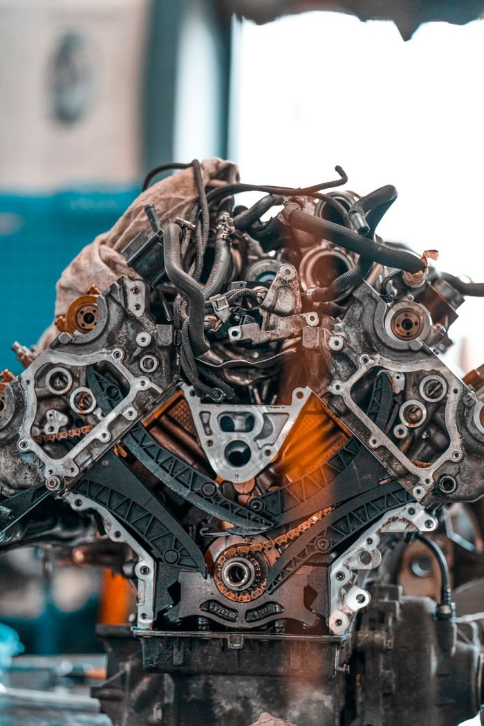 Home Car engine with various metal details placed on workbench in modern repair service