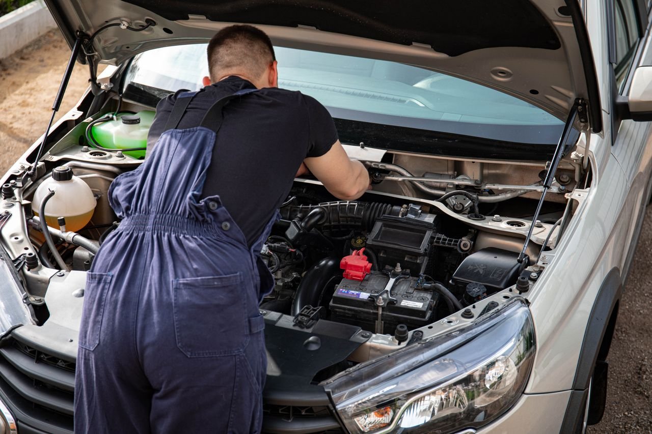Mastering the First Impression: Your intriguing post title goes here Close-up of mechanic repairing a car engine. Outdoor setting during the day.
