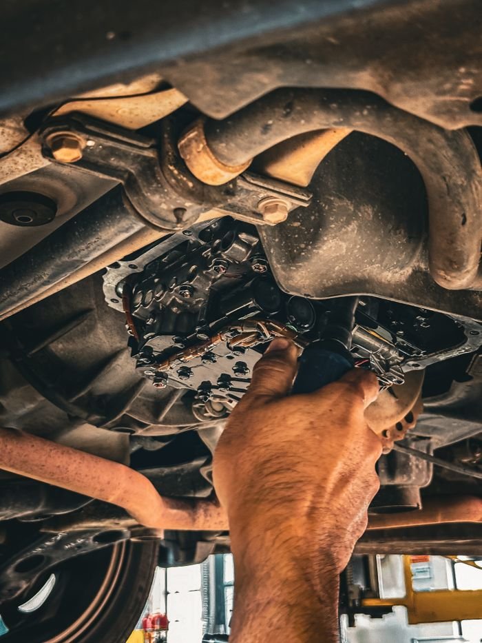 Offerings Mechanic working on car undercarriage in a garage setting.